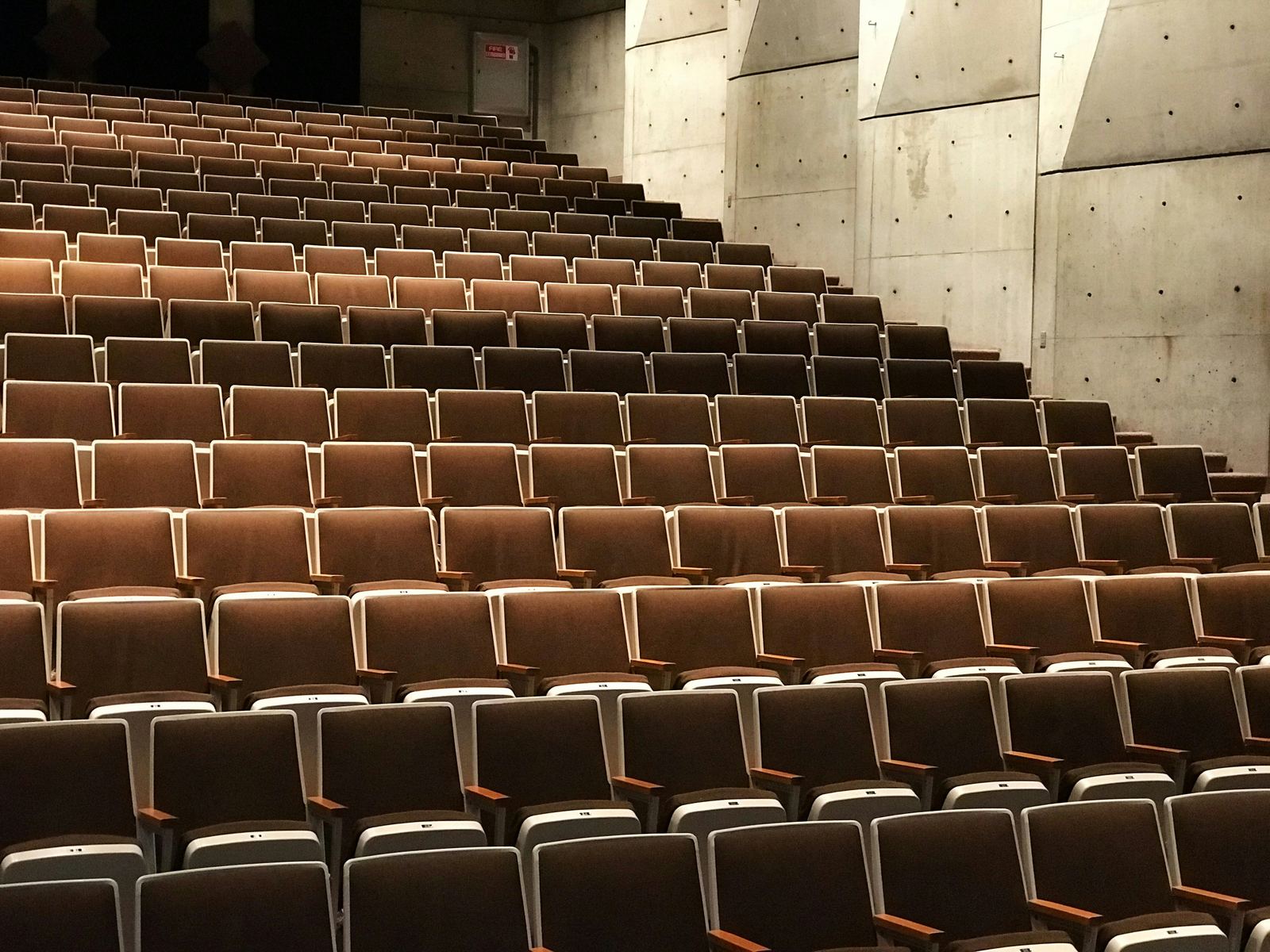 Rows of empty seats in an auditorium with concrete walls